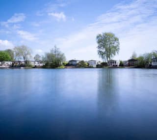 A photo of a riverside horizon during dawn of a row of static caravans. image