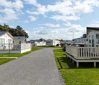 A stone path with holiday caravans seen on either side of the path.