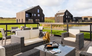 An outside area of one of our luxury barns with outside furniture. Over the balcony are two further lodges. image