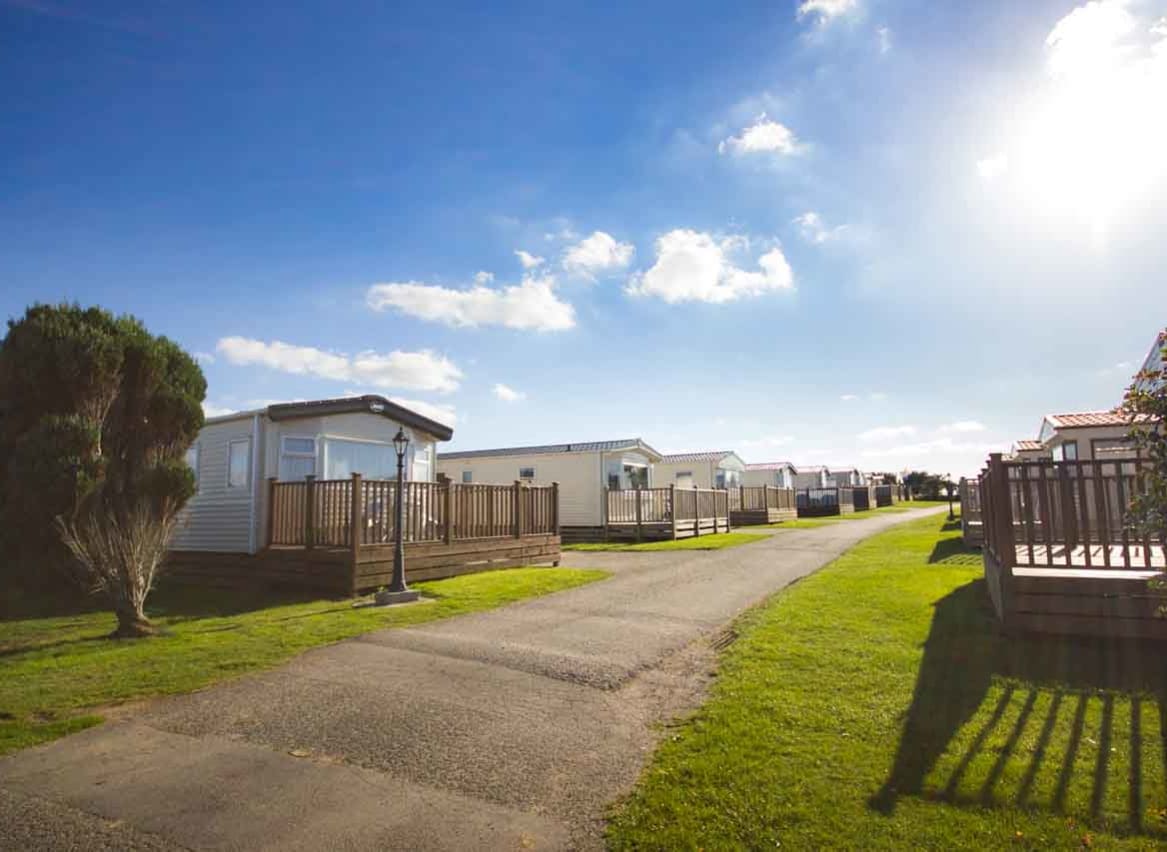 A wide pathway with holiday caravans on either side. Blue skies above. image