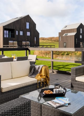 An outside area of one of our luxury barns with outside furniture. Over the balcony are two further lodges.