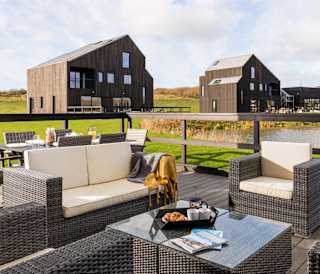 An outside area of one of our luxury barns with outside furniture. Over the balcony are two further lodges.