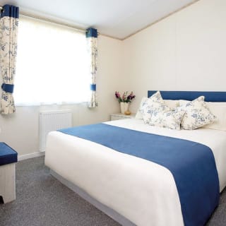 The interior of one of our Luxury holiday lodges. There's a large bedroom with a double bed and window.