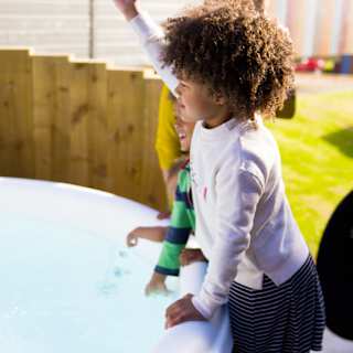Three young children playing outside one of the hot tubs at our Whitecliff Bay holiday park. image