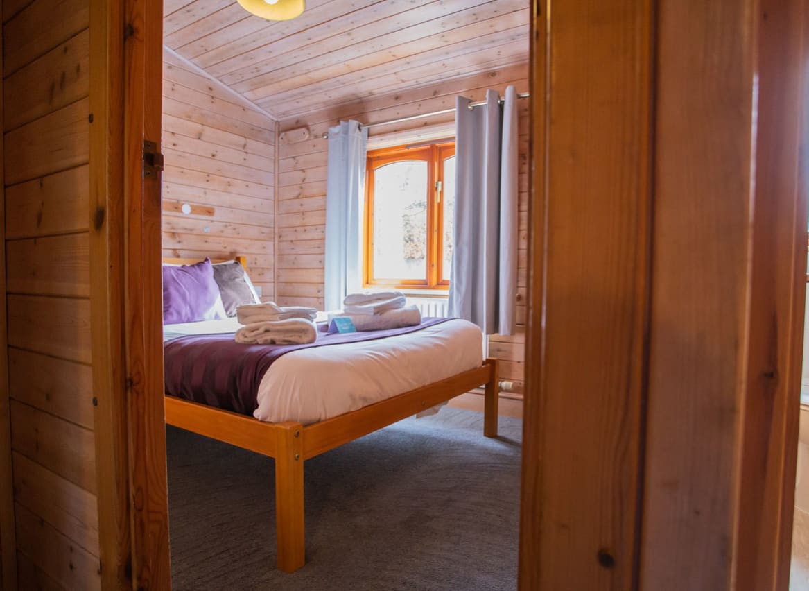 The interior of one of our woodland style holiday lodges. There's a doorway leading into a bedroom with a large double bed. image