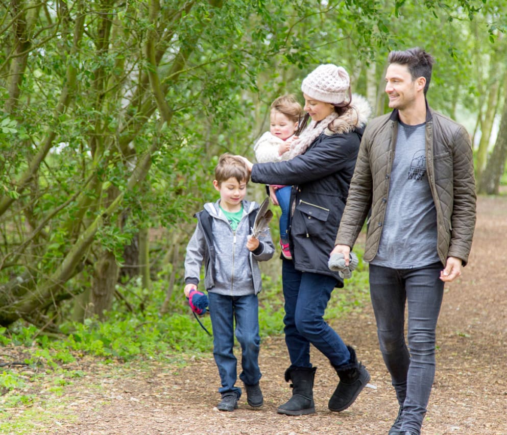 Family of four walking through trees together at Tattershall Lakes.