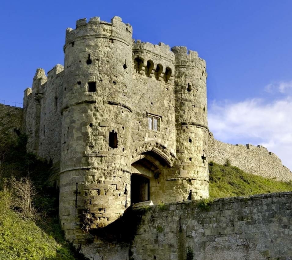 Carisbrooke Castle, Isle of Wight. The angle is looking up at the castle, viewing the bridge leading to the castle entrance. The sides of the castle are steep hills of grass. image