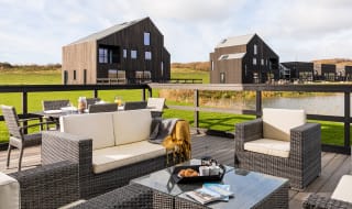 An outside area of one of our luxury barns with outside furniture. Over the balcony are two further lodges. image