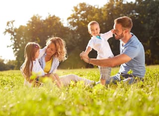 A young family playing in the grass outside on a sunny day. image