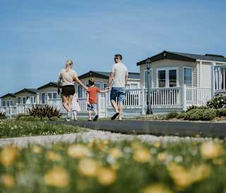 A young family walking past a row of caravans at our holiday park in Cornwall, Newperran.