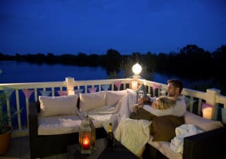 A couple cuddling on the decking of our holiday homes overlooking a lake.