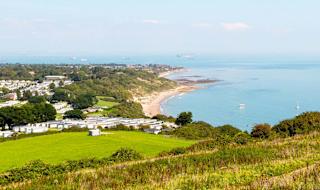 A view of our Whitecliff Bay holiday park. The cliffs are overlooking the sea, with plenty of boats cruising around. The coastline stretches far into the distance.