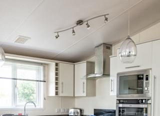 The interior of one of our Indulgent holiday lodges. There's a kitchen with various appliances and a island in the middle. image