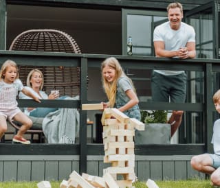 A family of five playing a game of jenga outside their accommodation.