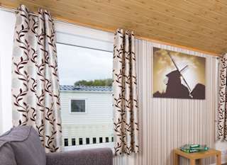 The interior of one of our Superior lodges. There are two grey sofas, a TV, and double-doors leading outside. image