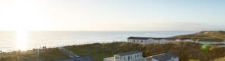 Two rows of caravans with views of the sea and the sun setting at our holiday park in North Wales, Barmouth Bay. image