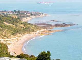 A view of our Whitecliff Bay holiday park. The cliffs are overlooking the sea, with plenty of boats cruising around. The coastline stretches far into the distance. image