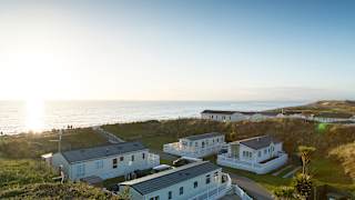 Two rows of caravans with views of the sea and the sun setting at our holiday park in North Wales, Barmouth Bay.