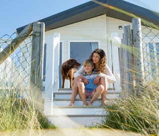 A mother, son and their chocolate lab dog sitting on the steps of one of our static caravans.