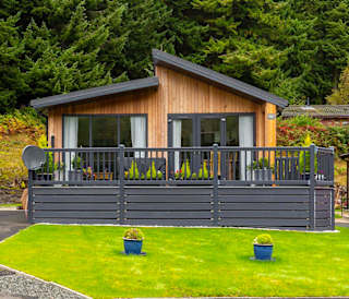 A photo of a wooden holiday lodge for sale. It has a dark grey wooden raised patio.