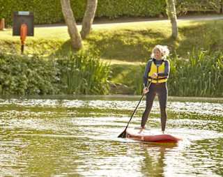 A woman paddleboarding on a sunny day through the lake at our Isle of Wight holiday park, The Lakes Rookley.