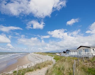A sunny, cloudy day overlooking the beach at Barmouth Bay, North Wales. Book now to stay in one of our luxury static caravans. image