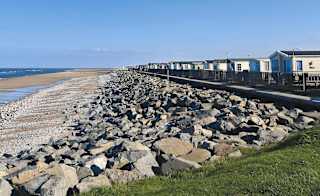 Our Golden Sands holiday park. The long beach stretches far into the distance, with rocks running along one side, and the sea on the other. image