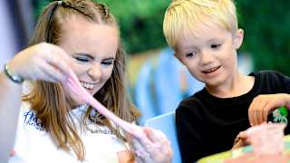 A young boy and one of our entertainment team members enjoying our slime workshop activity.