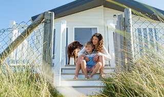 A mother, son and their chocolate lab dog sitting on the steps of one of our static caravans.