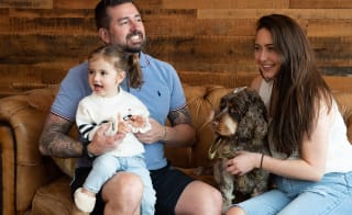 A family enjoying an afternoon bite to eat at The Lookout Bar & Eatery, Retallack. There is a mother and father, a young girl and their dog sat on the sofa. image