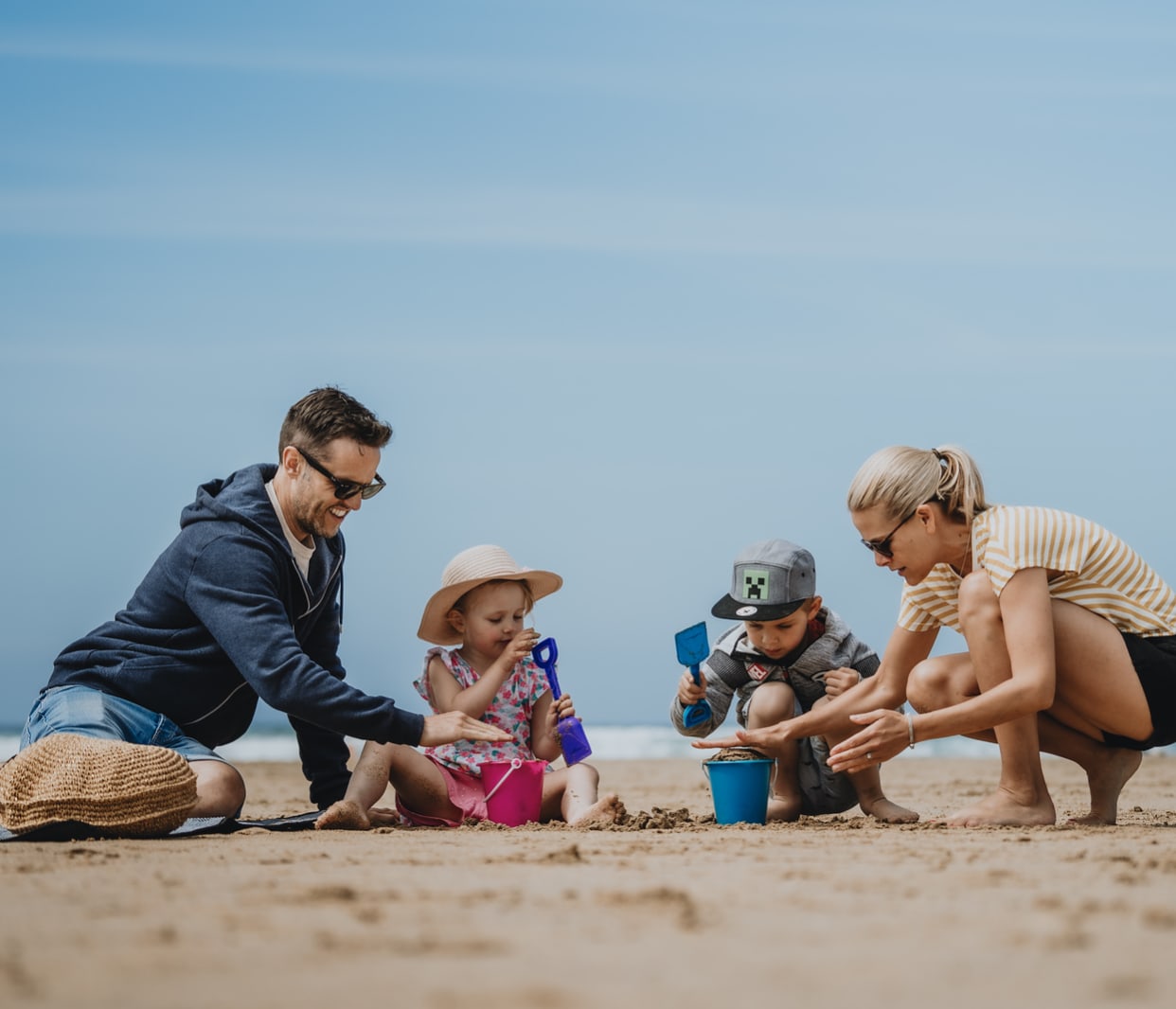 A family enjoying a summers day on the beach. There is a mother and father and two young children. image