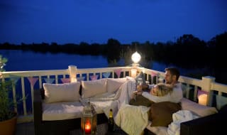 A couple cuddling on the decking of our holiday homes overlooking a lake. image