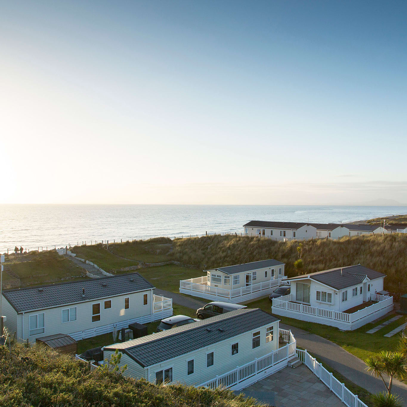 Two rows of caravans with views of the sea and the sun setting at our holiday park in North Wales, Barmouth Bay.