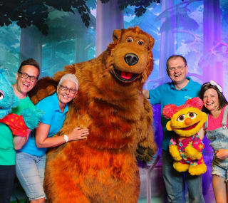 A group of people posing for a photo with the Away Resorts characters, Bear, Scratch and Lucy. image
