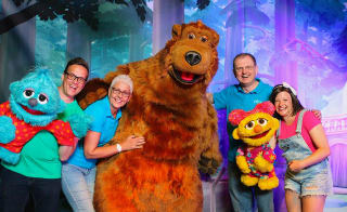A group of people posing for a photo with the Away Resorts characters, Bear, Scratch and Lucy. image