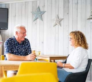 A couple enjoying a drink together at The Muddy Duck Clubhouse at our Essex holiday park, Mersea Island. image