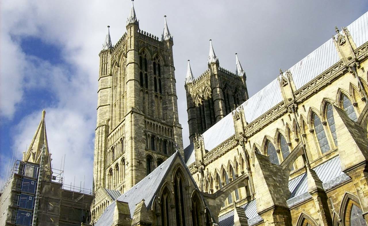 A photo of the Lincoln cathedral taken from below looking up at one of the spires on a cloudy day. image
