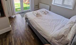 A double bedroom in one of the rooms within our cottages. opposite the double bed are french doors that lead to a garden area. To the right of the bed is a window, also looking out to the garden area. image