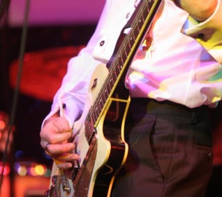 A close up image of a man playing a guitar. image