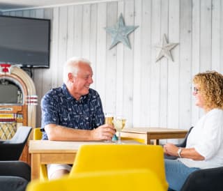 A couple enjoying a drink together at The Muddy Duck Clubhouse at our Essex holiday park, Mersea Island.