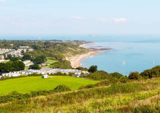 A view of our Whitecliff Bay holiday park. The cliffs are overlooking the sea, with plenty of boats cruising around. The coastline stretches far into the distance.