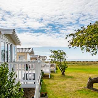 A row of caravans at our park in Essex, Mersea Island, with views of the sea in the background.