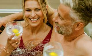 A couple enjoying a drink together in their hot tub. image