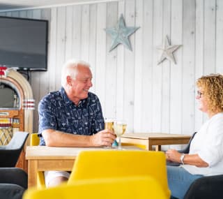 A couple enjoying a drink together at The Muddy Duck Clubhouse at our Essex holiday park, Mersea Island. image