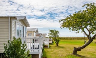 A row of caravans at our park in Essex, Mersea Island, with views of the sea in the background. image