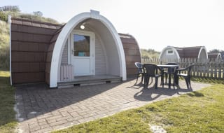 Exterior of our camping pod at St Ives Bay, Cornwall. A table and chair is located on the right, the perfect spot for brunch in the sunshine. image