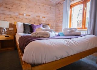 The interior of one of our woodland style holiday lodges. There's a bedroom with a double bed and window. image