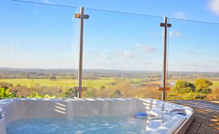 A closeup photo of an outdoor hot tub next to glass fencing on a bright sunny day at out holiday park in Sandy Balls, Hampshire. image