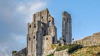 An image of Corfe Castle on a bright day with blue skies.