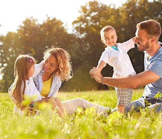 A young family playing in the grass outside on a sunny day.